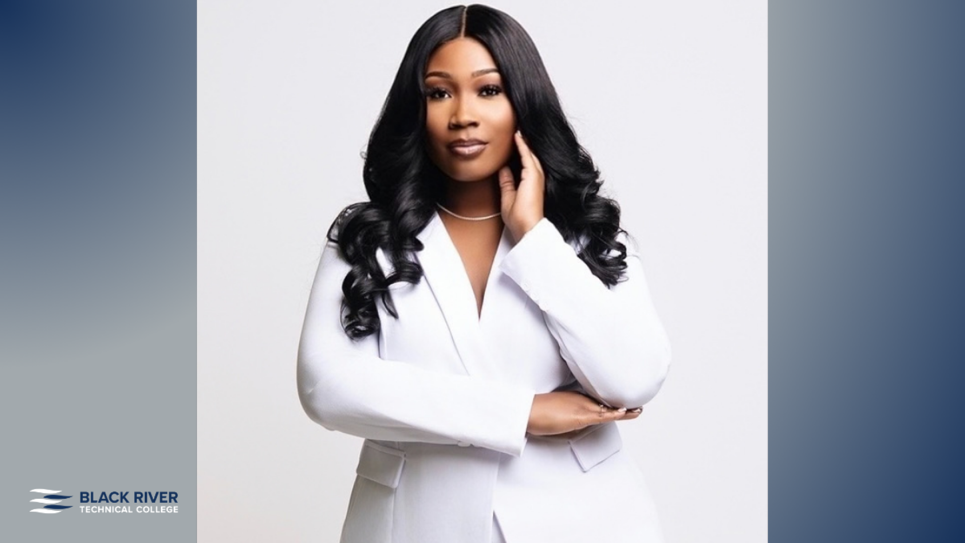 A woman with long dark curled hair, wearing a white blazer, poses against a plain light background, with Black River Technical College branding.